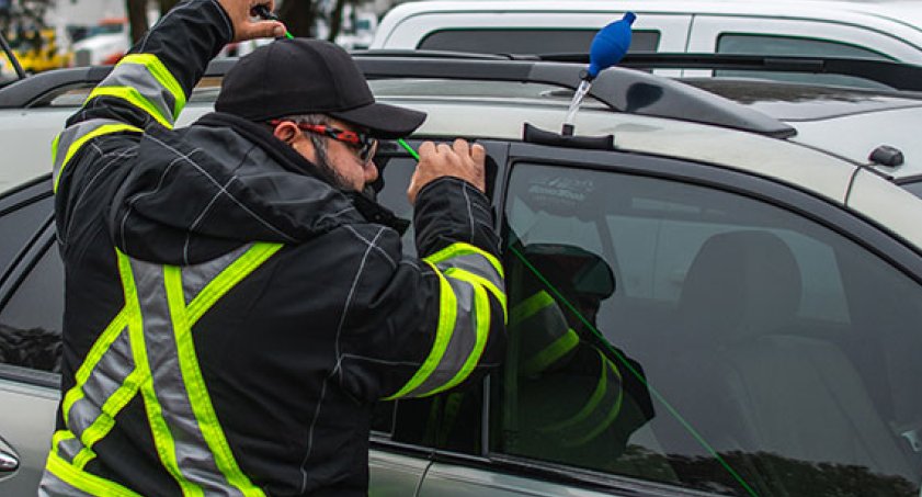 Technician opening a locked vehicle door with professional lockout tools
